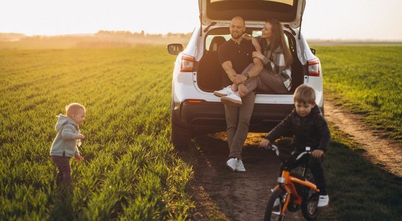 Young family with kids travelling by car, stopped in the field Young family with kids travelling by car, stopped in the field